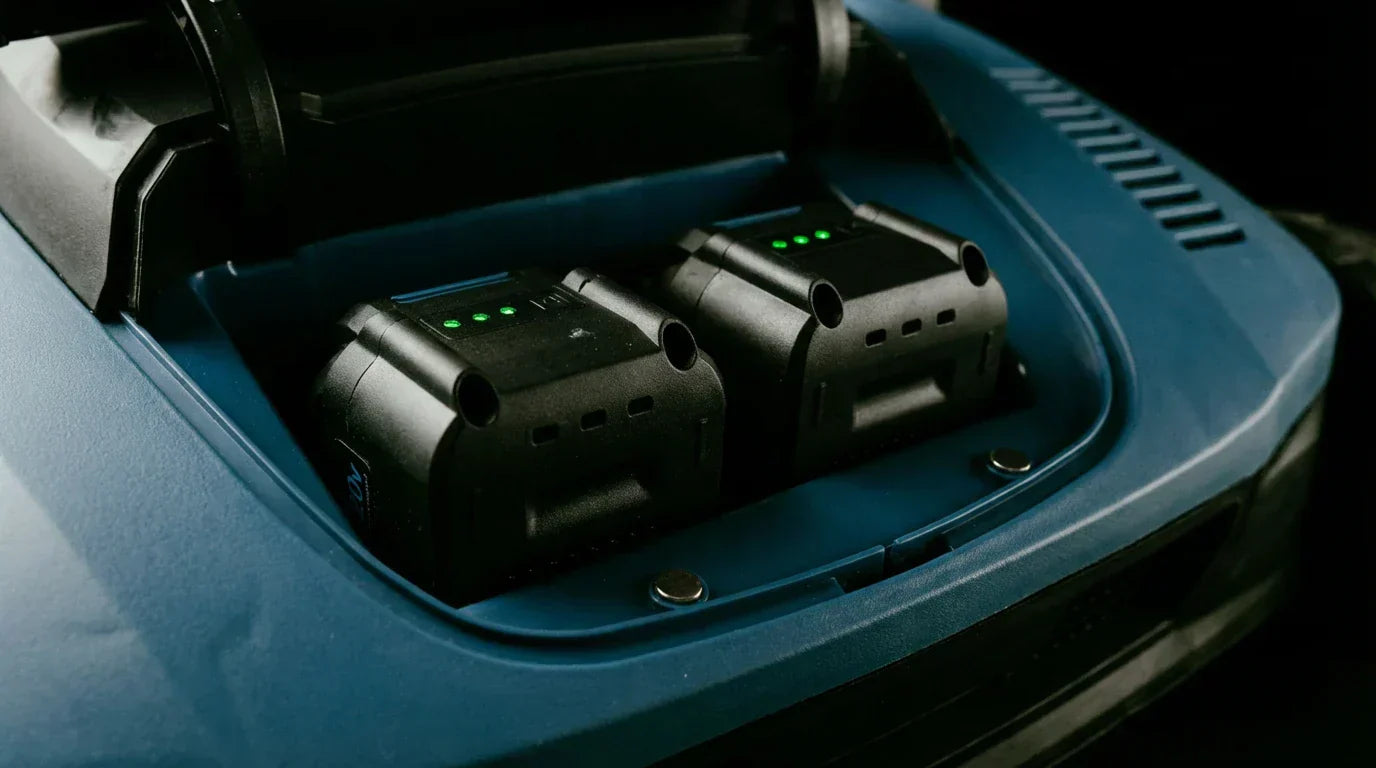 Close-up of TURFSPIN™ Cordless Artificial Turf Sweeper showing dual battery slots with charged batteries in a blue casing